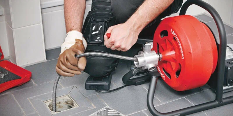 Plumber using a drain-cleaning machine in Warrington