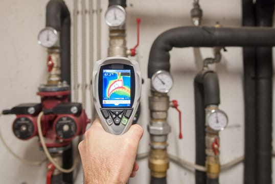 Plumber using a thermal imaging camera to inspect pipes in Warrington