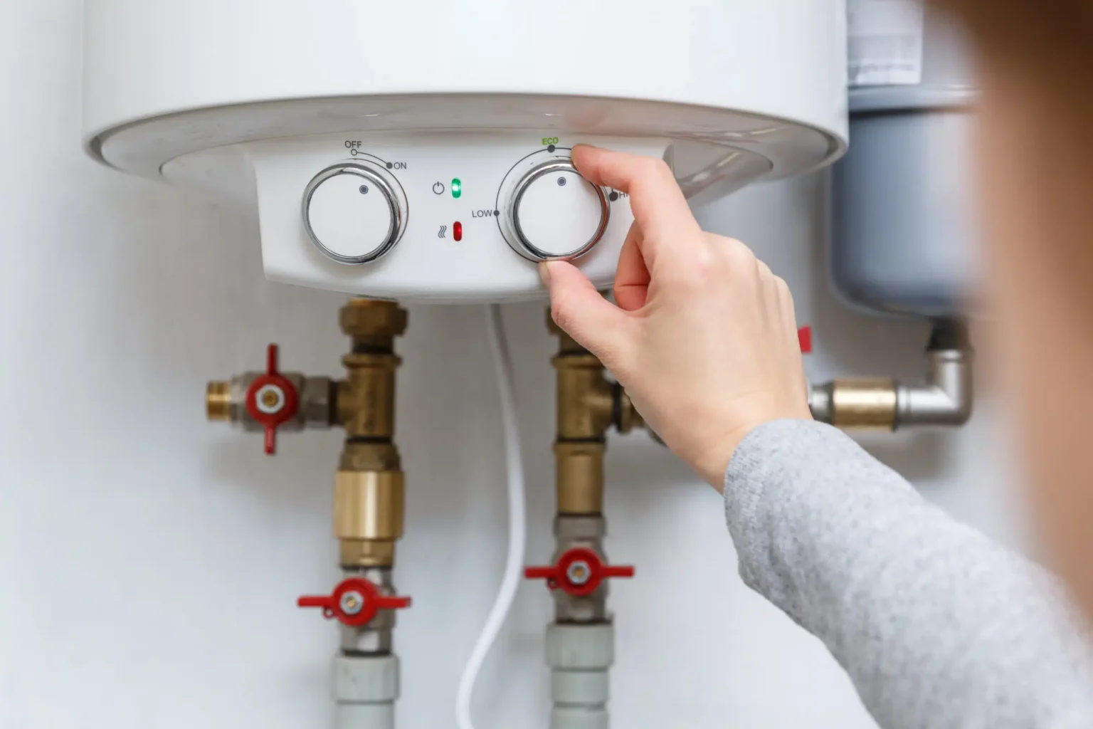 Homeowner adjusting the temperature controls on a water heater in Warrington